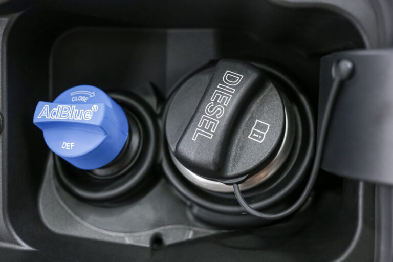 Gros plan sur le bouchon du réservoir AdBlue à côté de l'entrée du gasoil, illustrant les risques de confusion